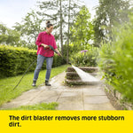 Load image into Gallery viewer, A woman in a pink shirt and jeans uses a high-pressure water hose to wash a stone garden path, with a bright yellow text banner at the bottom reading 'The dirt blaster removes more stubborn dirt.'.