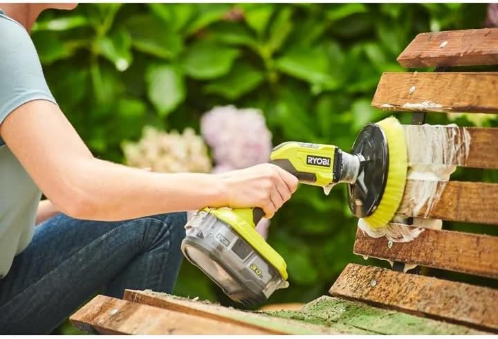 Person using a Ryobi sander on wooden furniture outdoors