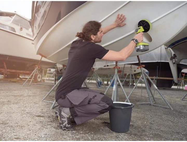 Man cleaning a boat with a scrubber in a marina setting