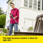Woman using a high-pressure washer in front of a house