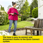 Load image into Gallery viewer, Woman using a pressure washer to clean a wooden bench in a garden.