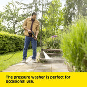 Person using a pressure washer on stone steps with greenery in the background