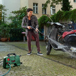 Load image into Gallery viewer, Man using a pressure washer to clean a motorcycle on a driveway.